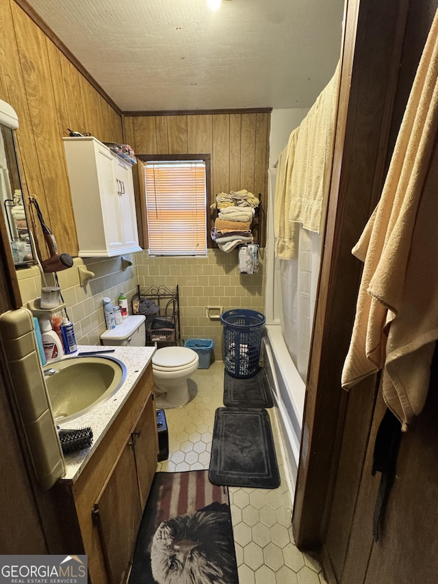 full bathroom featuring shower / bath combo, backsplash, vanity, toilet, and wood walls