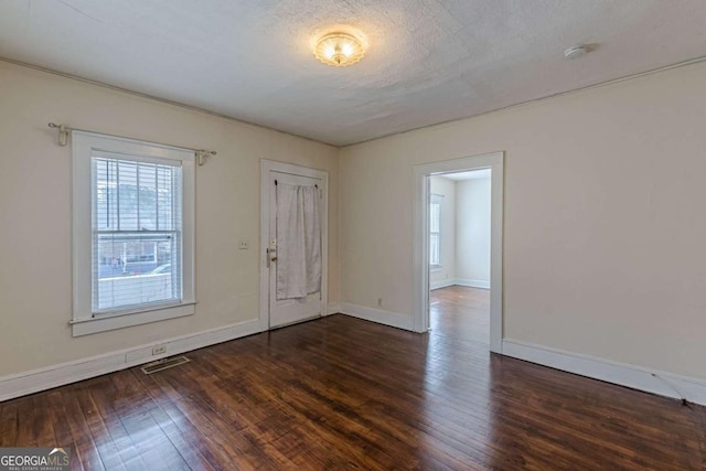 spare room with dark hardwood / wood-style flooring and a textured ceiling