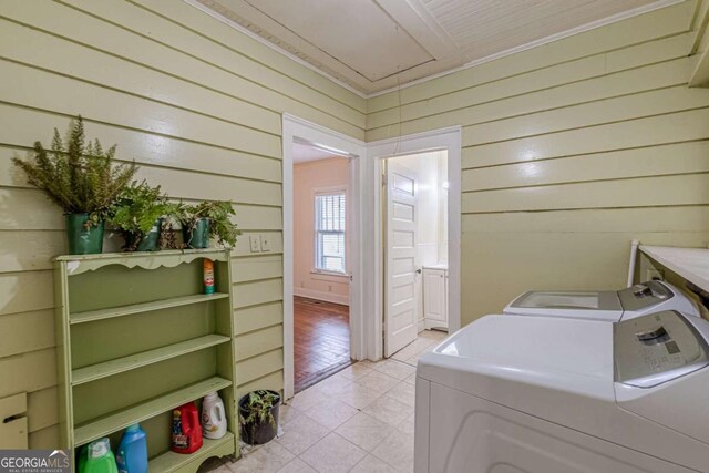 laundry room featuring light tile patterned flooring, washing machine and clothes dryer, and wood walls