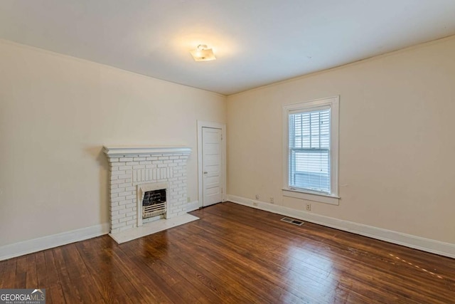 unfurnished living room with a brick fireplace and dark hardwood / wood-style flooring