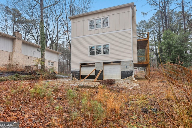 back of property with a garage, board and batten siding, and a sunroom