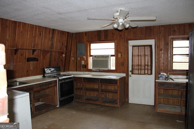 kitchen featuring gas range, wood walls, and a wealth of natural light