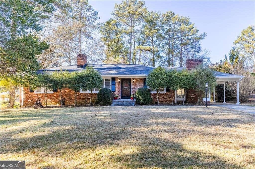 ranch-style home featuring a carport and a front lawn