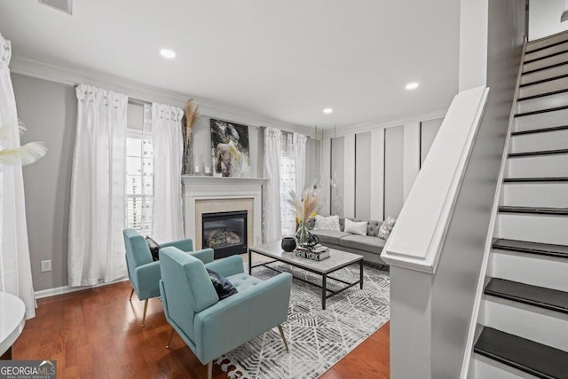 living room featuring crown molding, a wealth of natural light, a fireplace, and dark hardwood / wood-style flooring