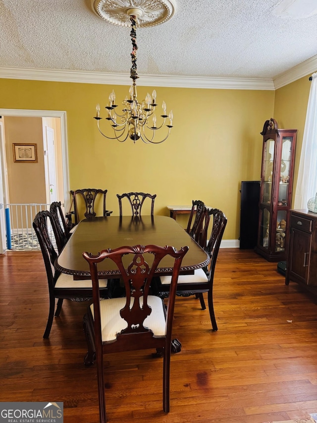 dining room with hardwood / wood-style floors, a textured ceiling, and a notable chandelier