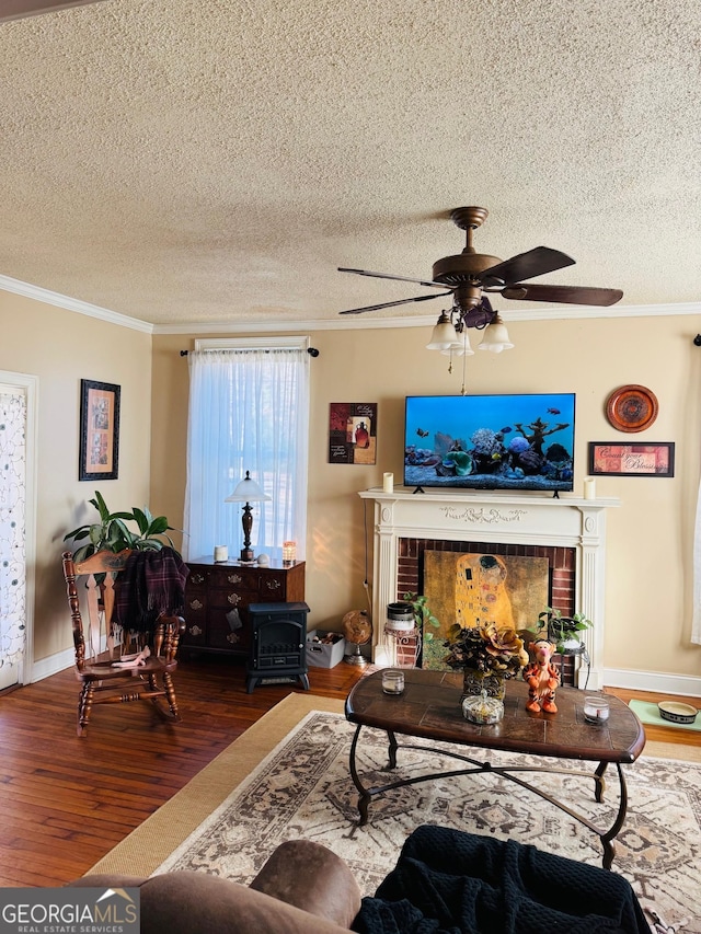 living room featuring ornamental molding, a fireplace, hardwood / wood-style floors, and a textured ceiling