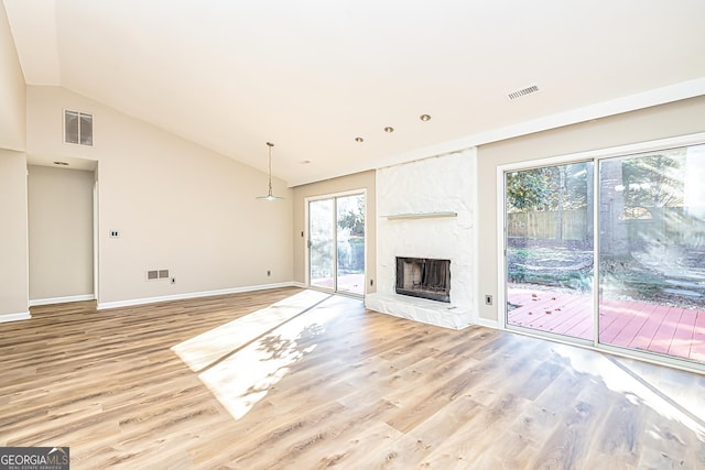 unfurnished living room with vaulted ceiling, a large fireplace, and light wood-type flooring