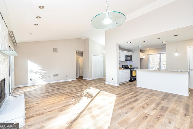 unfurnished living room featuring a large fireplace, high vaulted ceiling, and light hardwood / wood-style floors