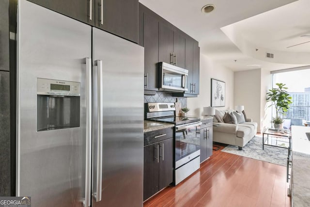 kitchen featuring ceiling fan, stainless steel appliances, wood-type flooring, and decorative backsplash