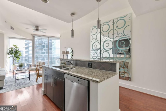 kitchen featuring dark wood-type flooring, light stone counters, stainless steel dishwasher, pendant lighting, and a wall of windows