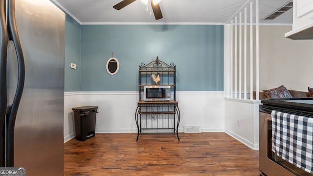 interior space featuring crown molding, ceiling fan, stainless steel appliances, and dark wood-type flooring