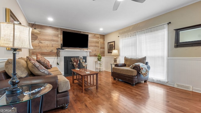 living room featuring wood-type flooring, ornamental molding, and ceiling fan