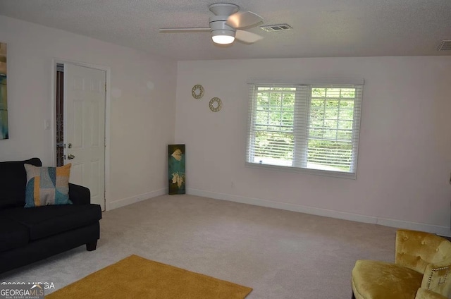 living room featuring ceiling fan, light carpet, and a textured ceiling