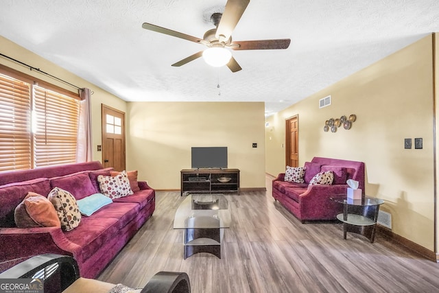 living room with ceiling fan, wood-type flooring, and a textured ceiling