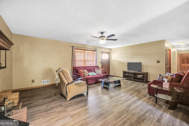 living room featuring ceiling fan, wood-type flooring, and a textured ceiling