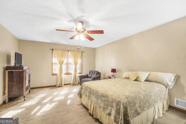 bedroom featuring light colored carpet, a textured ceiling, and ceiling fan