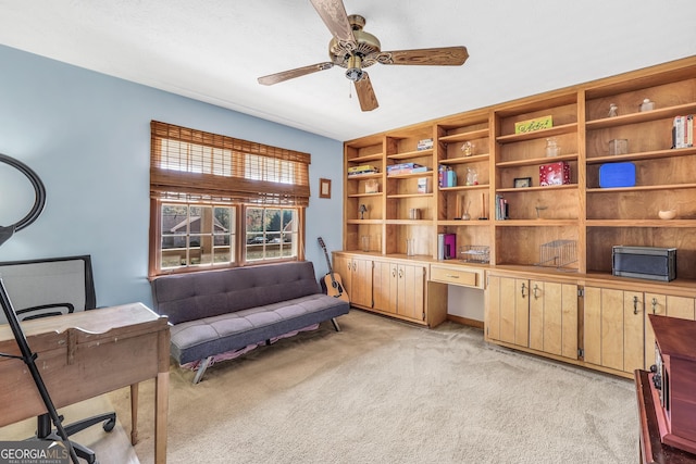 sitting room with light carpet, built in desk, and ceiling fan