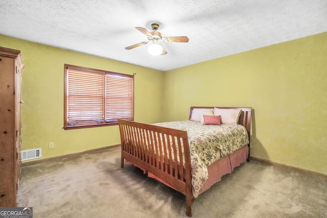 bedroom with ceiling fan, carpet flooring, and a textured ceiling