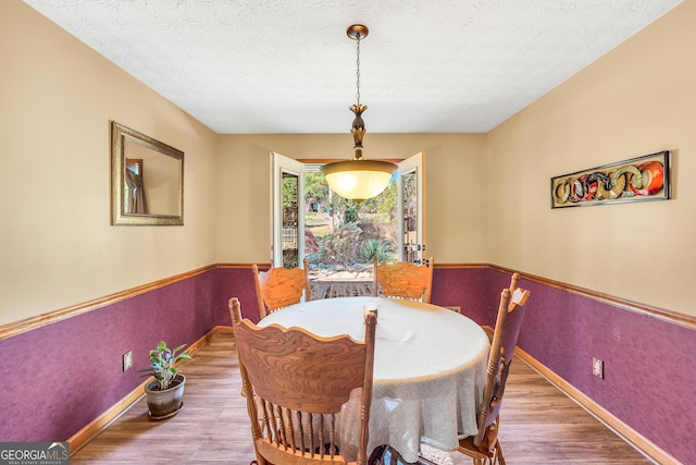 dining room with wood-type flooring and a textured ceiling