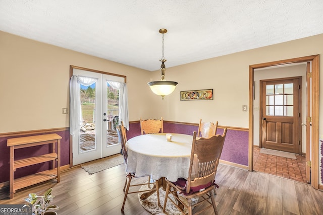 dining area with dark hardwood / wood-style floors, french doors, and a textured ceiling