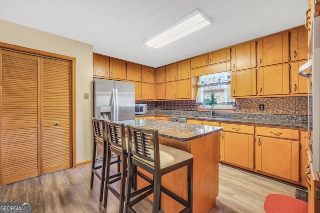 kitchen with a kitchen island, a breakfast bar area, decorative backsplash, and appliances with stainless steel finishes