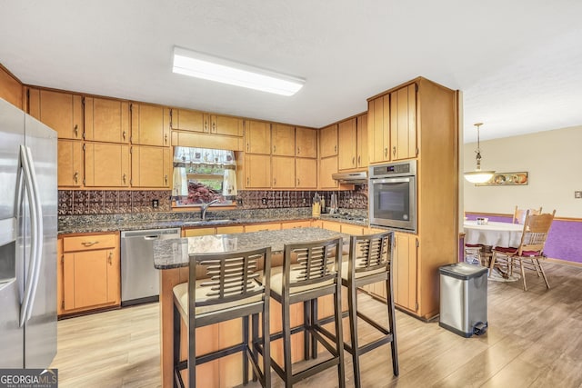 kitchen featuring a kitchen island, tasteful backsplash, sink, stainless steel appliances, and light wood-type flooring