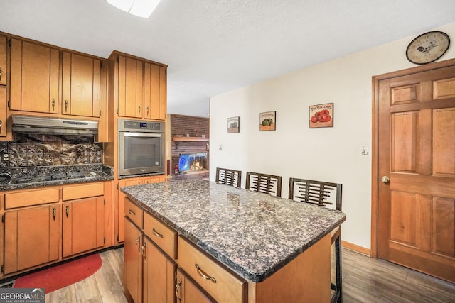 kitchen with a kitchen island, hardwood / wood-style floors, oven, and black gas cooktop