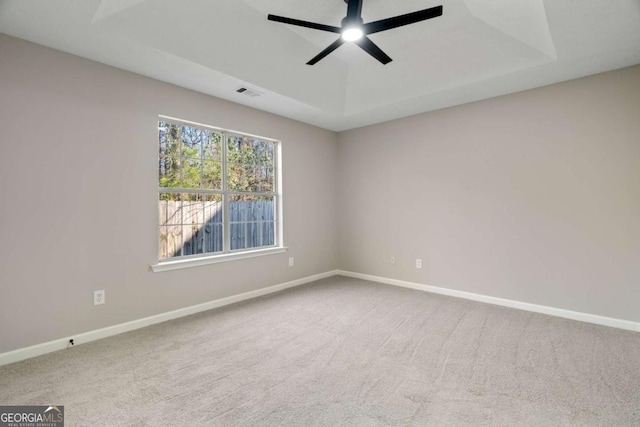 carpeted spare room with ceiling fan and a tray ceiling