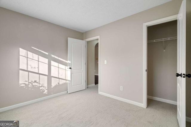 unfurnished bedroom with light carpet, a closet, and a textured ceiling