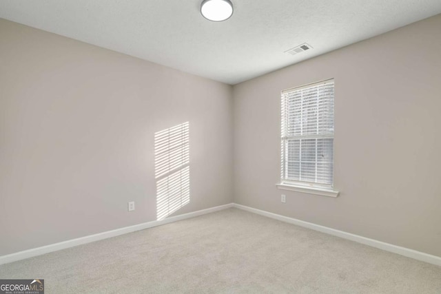 unfurnished room featuring light colored carpet and a textured ceiling