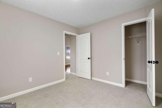 unfurnished bedroom with light colored carpet and a closet