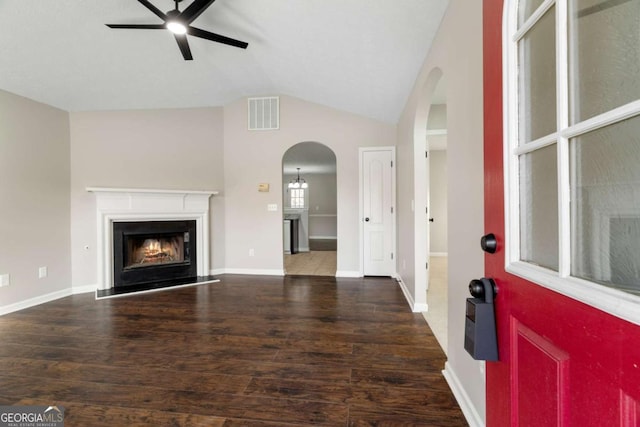 living room with dark wood-type flooring, ceiling fan, and vaulted ceiling