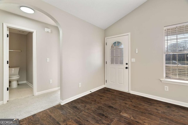 foyer entrance with dark wood-type flooring and vaulted ceiling