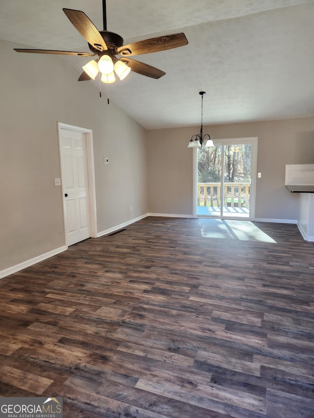 interior space featuring lofted ceiling, ceiling fan with notable chandelier, and dark hardwood / wood-style flooring