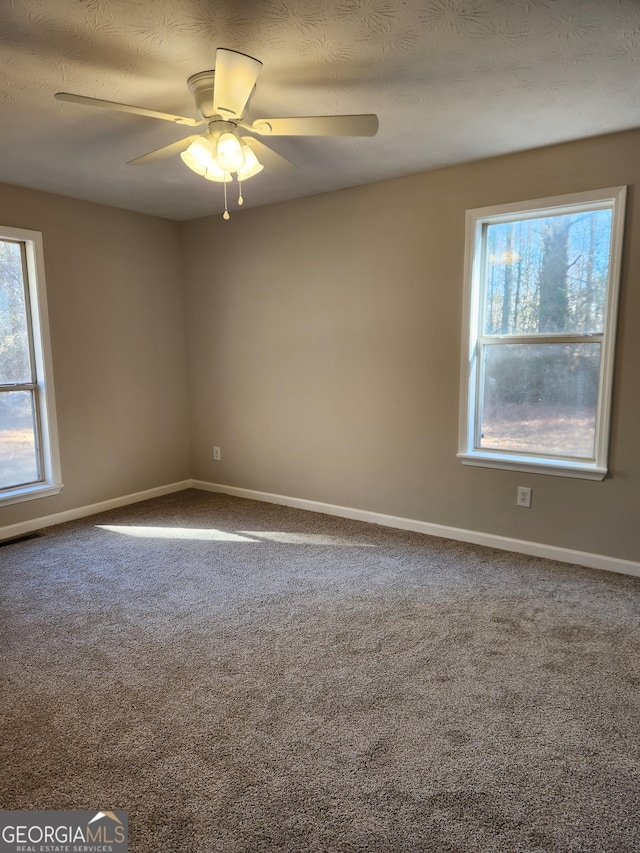 empty room with ceiling fan, carpet flooring, and a textured ceiling