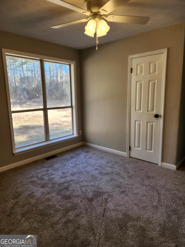 spare room with a textured ceiling, ceiling fan, and carpet