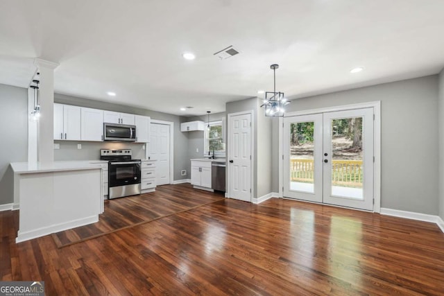 kitchen with white cabinetry, stainless steel appliances, dark hardwood / wood-style flooring, and kitchen peninsula