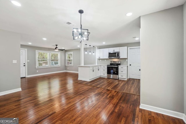 kitchen featuring stainless steel appliances, white cabinetry, dark hardwood / wood-style flooring, and kitchen peninsula