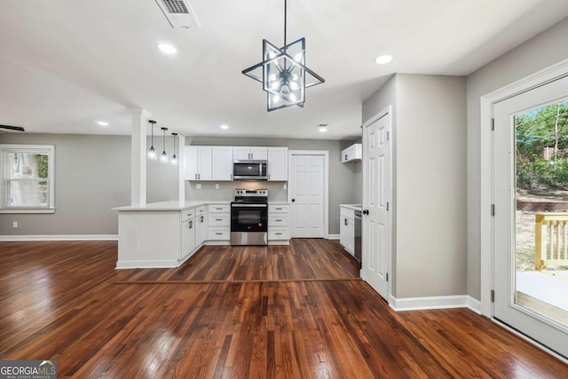 kitchen with decorative light fixtures, white cabinetry, kitchen peninsula, stainless steel appliances, and dark wood-type flooring