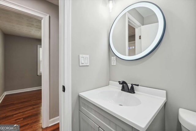 bathroom with vanity, wood-type flooring, and toilet