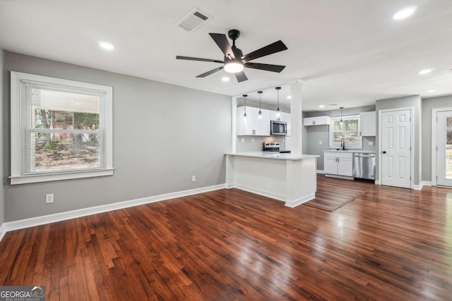 kitchen with sink, appliances with stainless steel finishes, white cabinets, decorative light fixtures, and kitchen peninsula