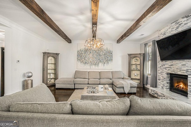 living room featuring dark hardwood / wood-style floors, a stone fireplace, an inviting chandelier, and beam ceiling