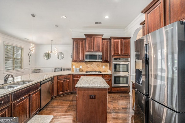 kitchen featuring sink, crown molding, a center island, appliances with stainless steel finishes, and pendant lighting