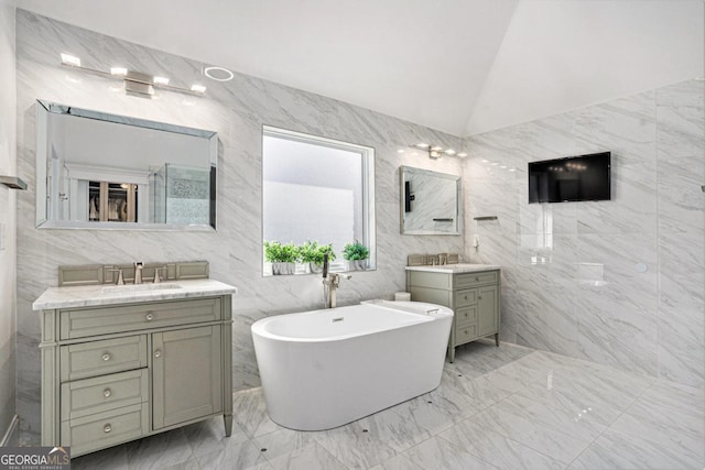 bathroom with vanity, vaulted ceiling, a tub, and tile walls