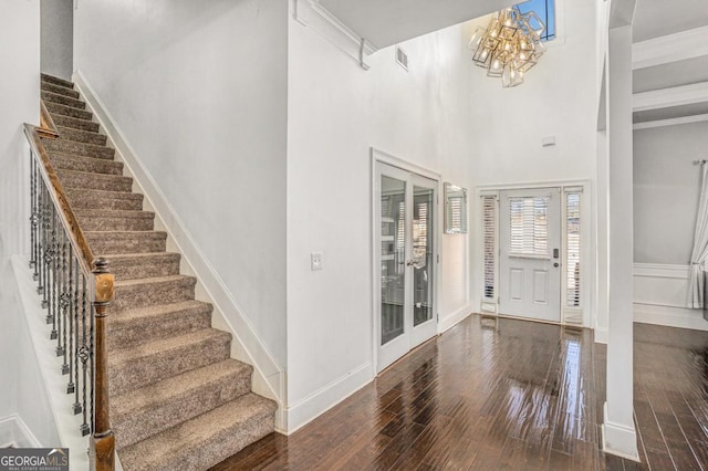 entryway with a towering ceiling, dark hardwood / wood-style floors, and a notable chandelier