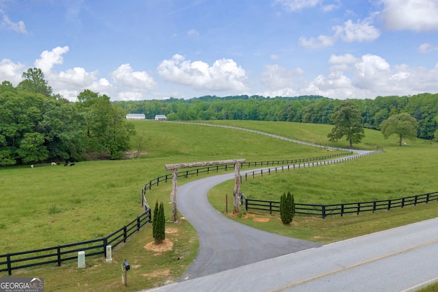 view of property's community with fence, a lawn, and a rural view