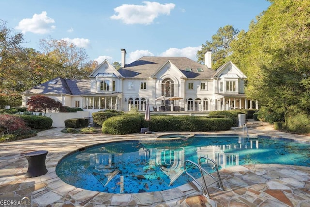 rear view of house with a pool with hot tub and a patio