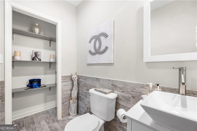 bathroom with vanity, tile walls, and toilet