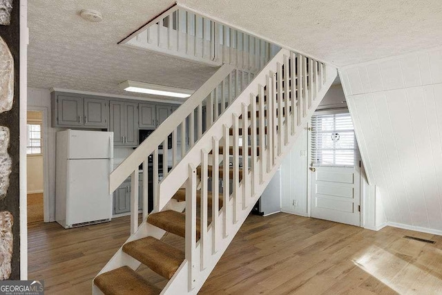 stairway with hardwood / wood-style floors and a textured ceiling