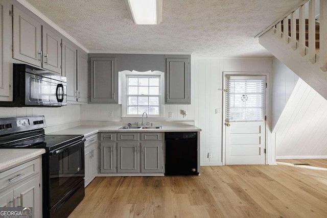 kitchen featuring sink, crown molding, light hardwood / wood-style flooring, gray cabinets, and black appliances